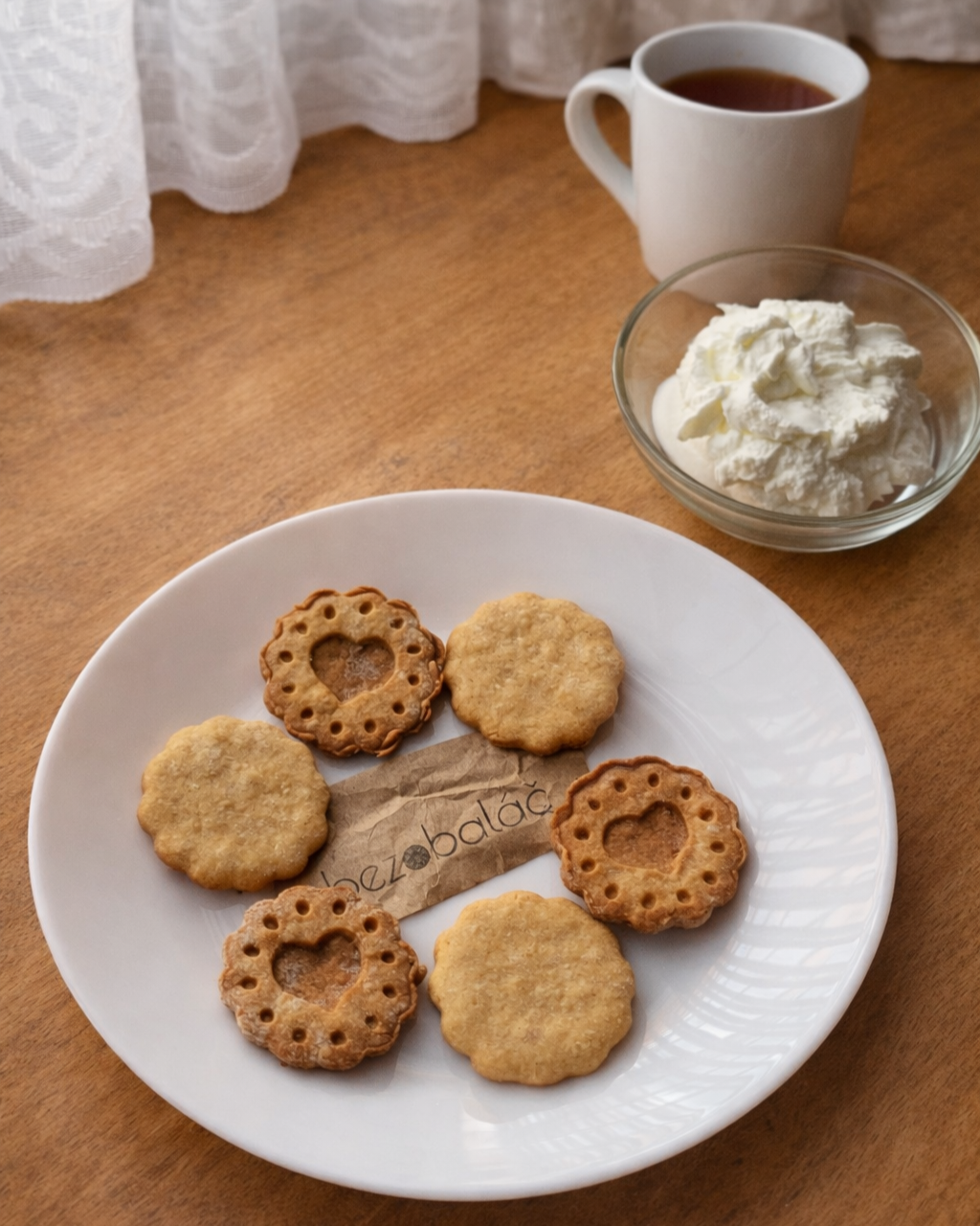 Linecké cukroví bez rafinovaného cukru na bílém talíři, tip na servírování s tvarohem a šálkem čaje